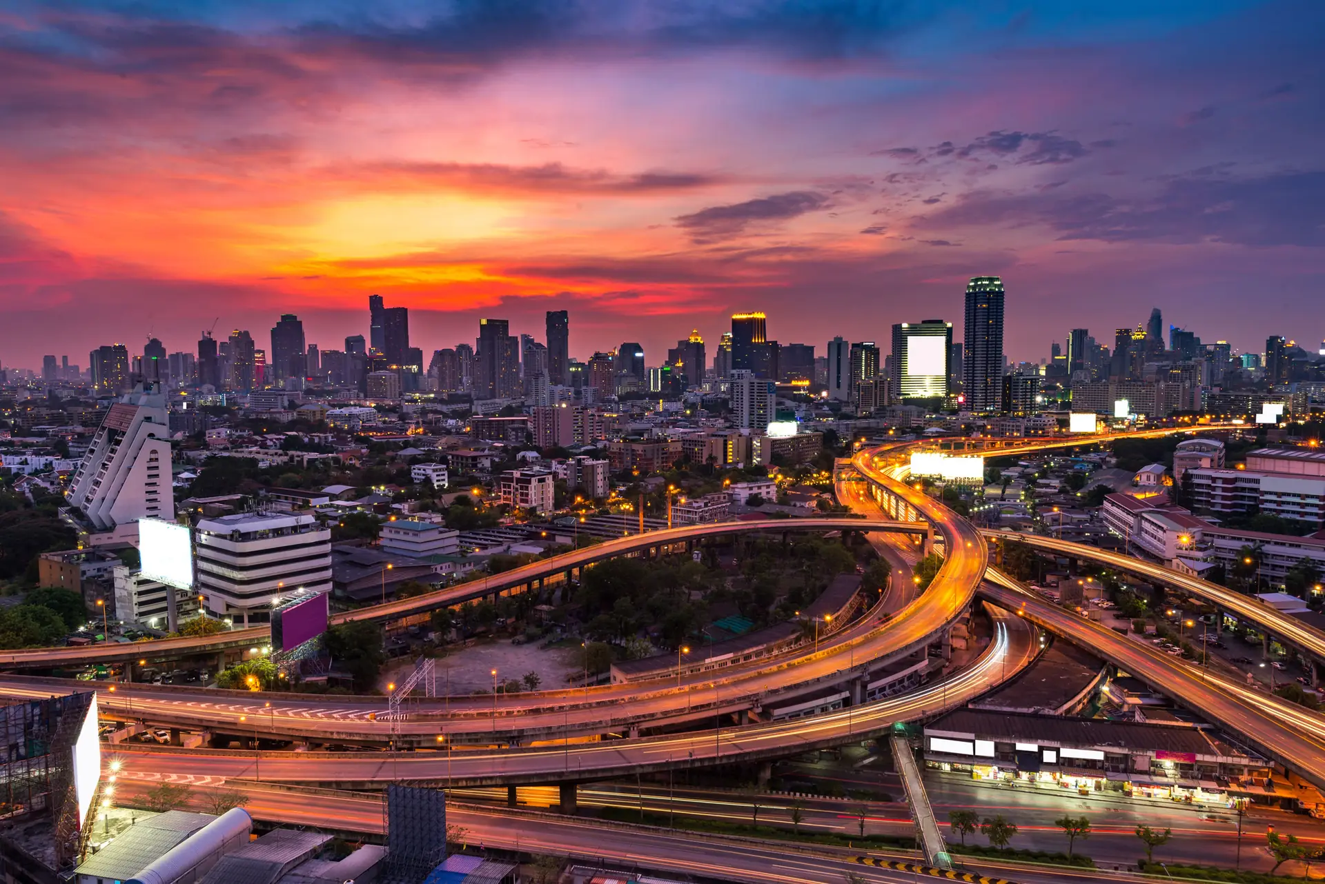 Aerial view of central Bangkok's skyline and expressway interchanges at sunset, Thailand