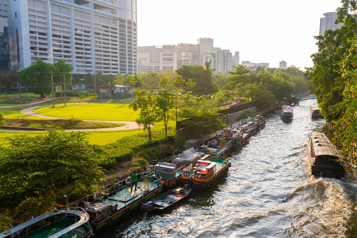 Canal boats and riverside parkland in the Thonburi–Khlong San district of Bangkok, Thailand