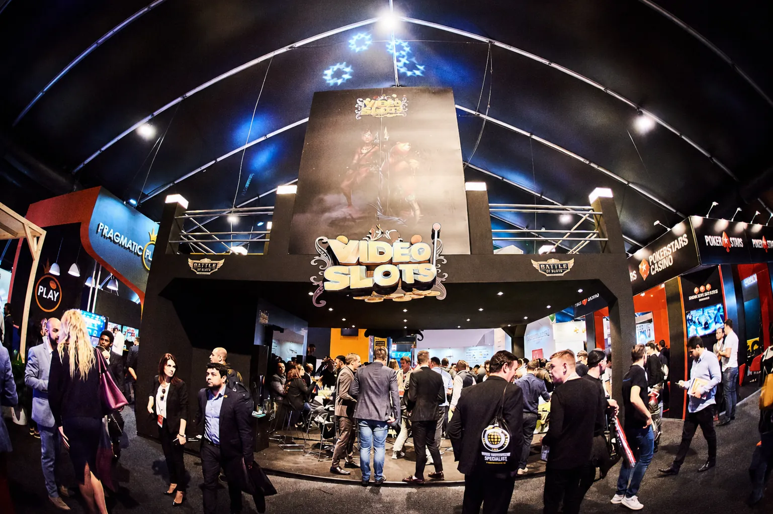 Crowded iGaming exhibition floor with large branded operator stands and delegates networking between them