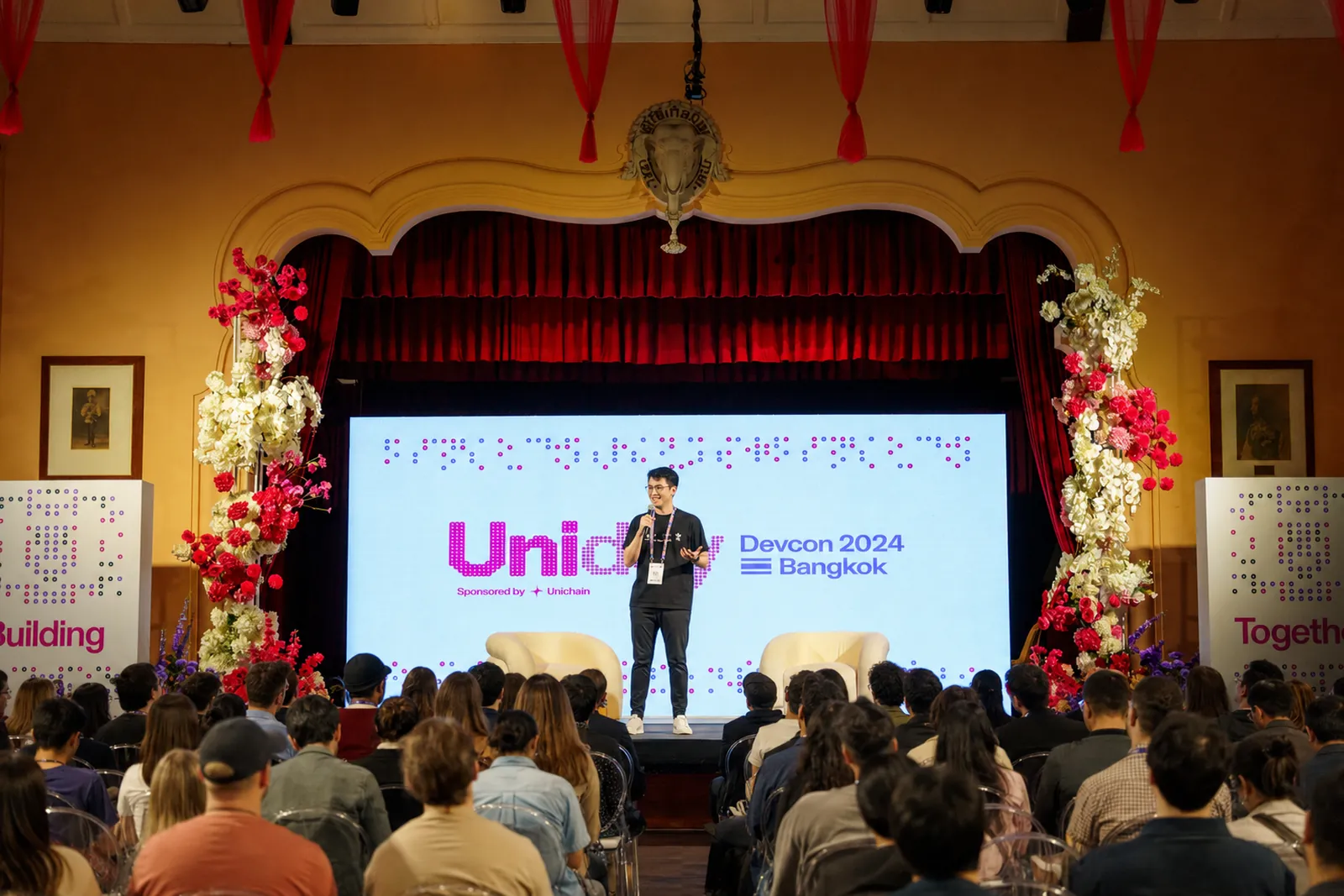 Speaker on stage at Uniday during Devcon 2024 in Bangkok, with a seated audience facing the stage