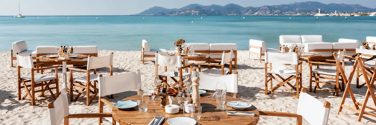 Set tables and yellow parasols on the sand at Miramar Plage, Cannes