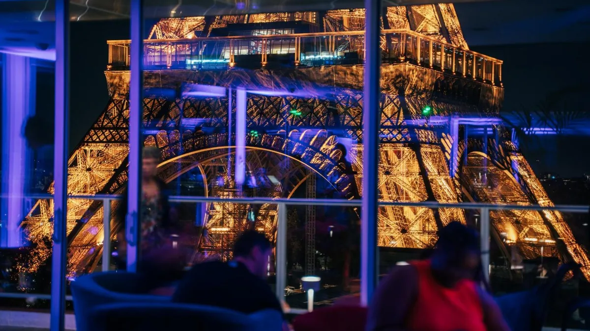 The Eiffel Tower lit at night through the glass frontage of the Pullman Paris Tour Eiffel
