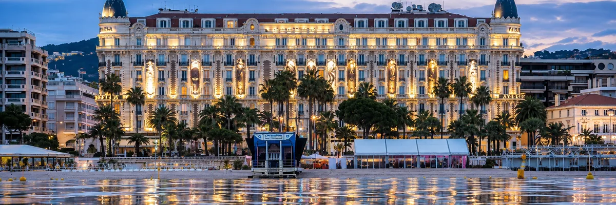 The Regent Carlton Cannes lit at dusk seen from the beach