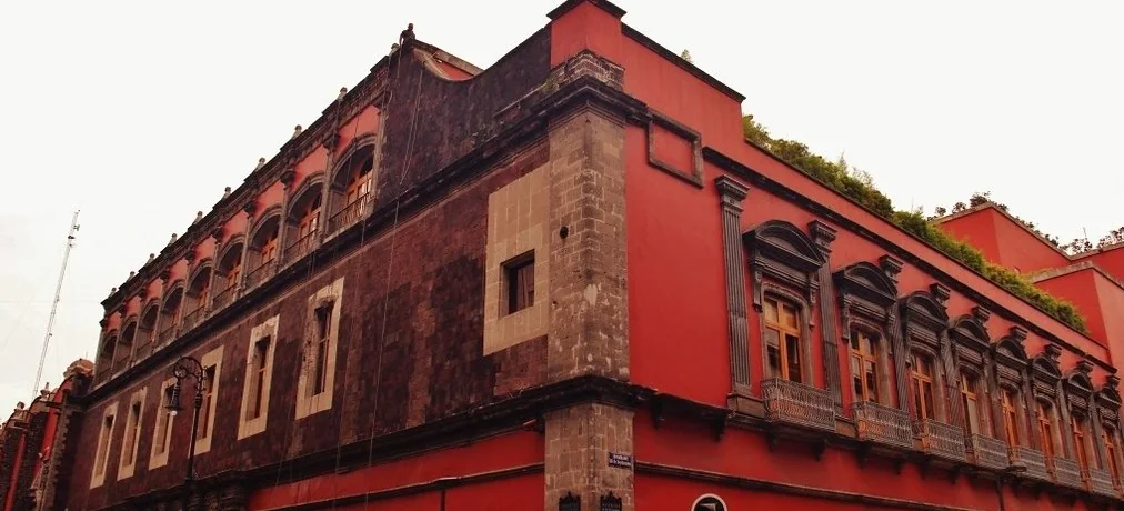Red tezontle and stone corner facade with iron balconies at the Bankers Club of Mexico, Centro Histórico