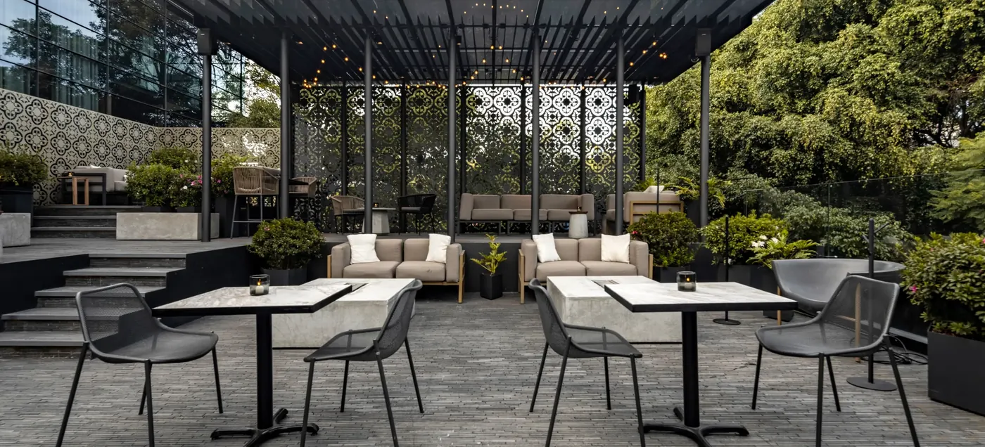 Terrace under a dark canopy with patterned screens and lounge seating at Brick Hotel, Roma Norte, Mexico City