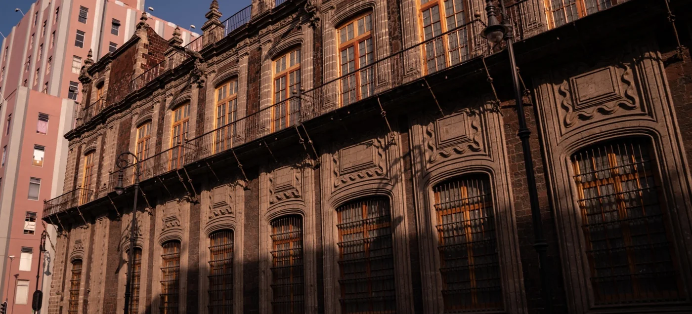 Carved stone facade with ornate window surrounds and iron balconies at Foro Valparaíso, Centro Histórico, Mexico City