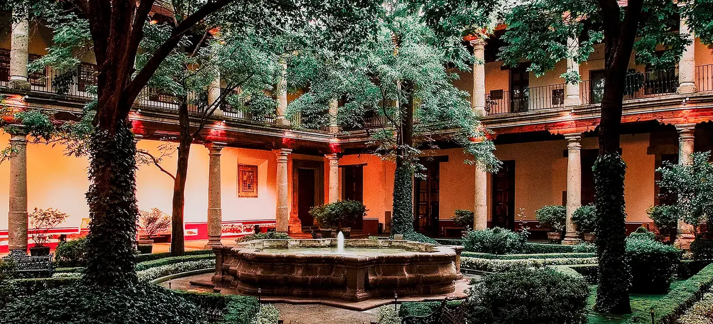 Colonial cloister courtyard with a stone fountain, clipped hedges and a colonnaded arcade at Museo Franz Mayer, Centro Histórico, Mexico City