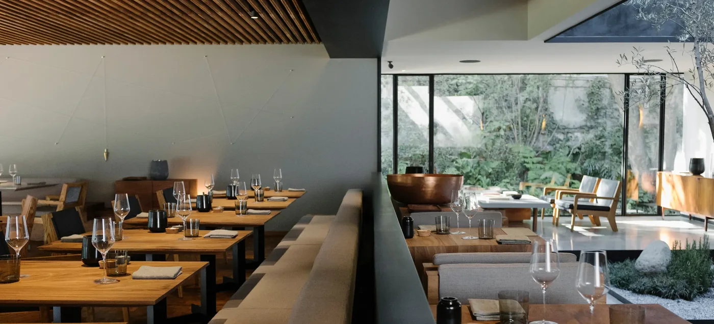 Timber-slatted dining room with banquette seating and a courtyard outlook at Pujol, Polanco, Mexico City