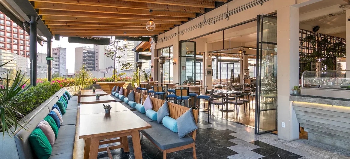 Covered rooftop terrace with banquette seating and folding glass doors at Terraza Cha Cha Chá, Tabacalera, Mexico City